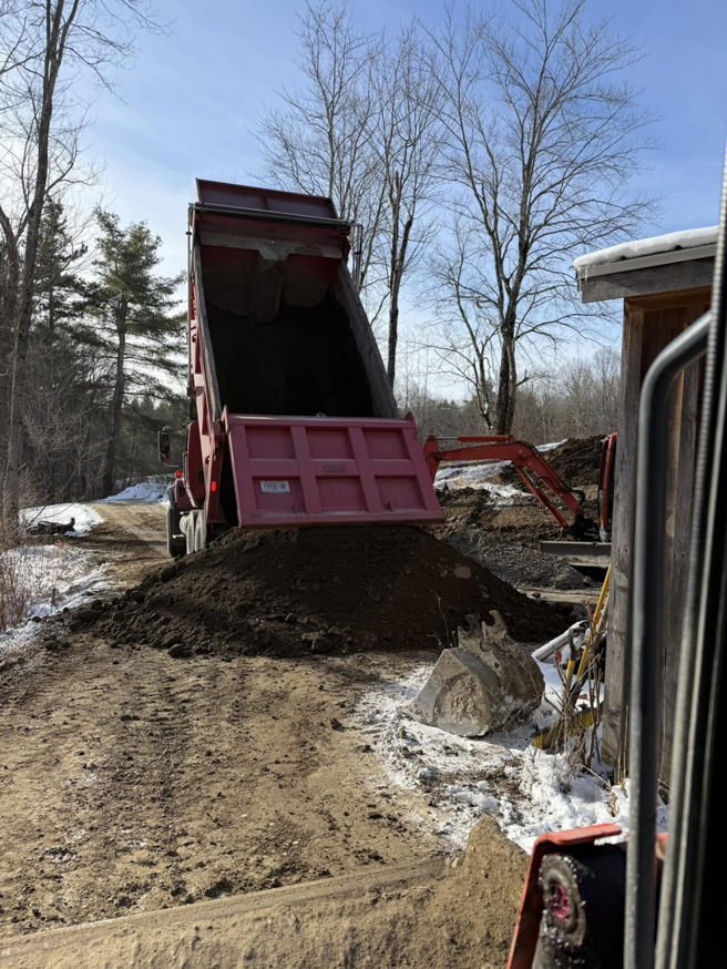 A red dump truck unloading gravel for site preparation by Naz General Contracting LLC in Schenectady, NY.