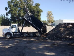 A dump truck unloading material onto a large pile at Global Recycling of Tampa Bay in Tampa, FL.