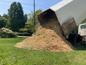 A dump truck unloading a large pile of wood chips for mulching by GKC Landscaping Contractors in Thornton, CO.