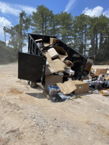 A dump trailer from The Dump Bros LLC actively dumping a large load of cardboard and junk in Raleigh, NC.