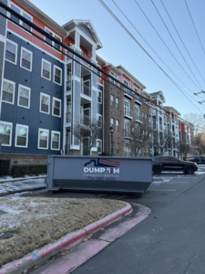 A Dump 'Em Dumpster Rentals dumpster placed in the parking lot of an apartment complex in Charlotte, NC.