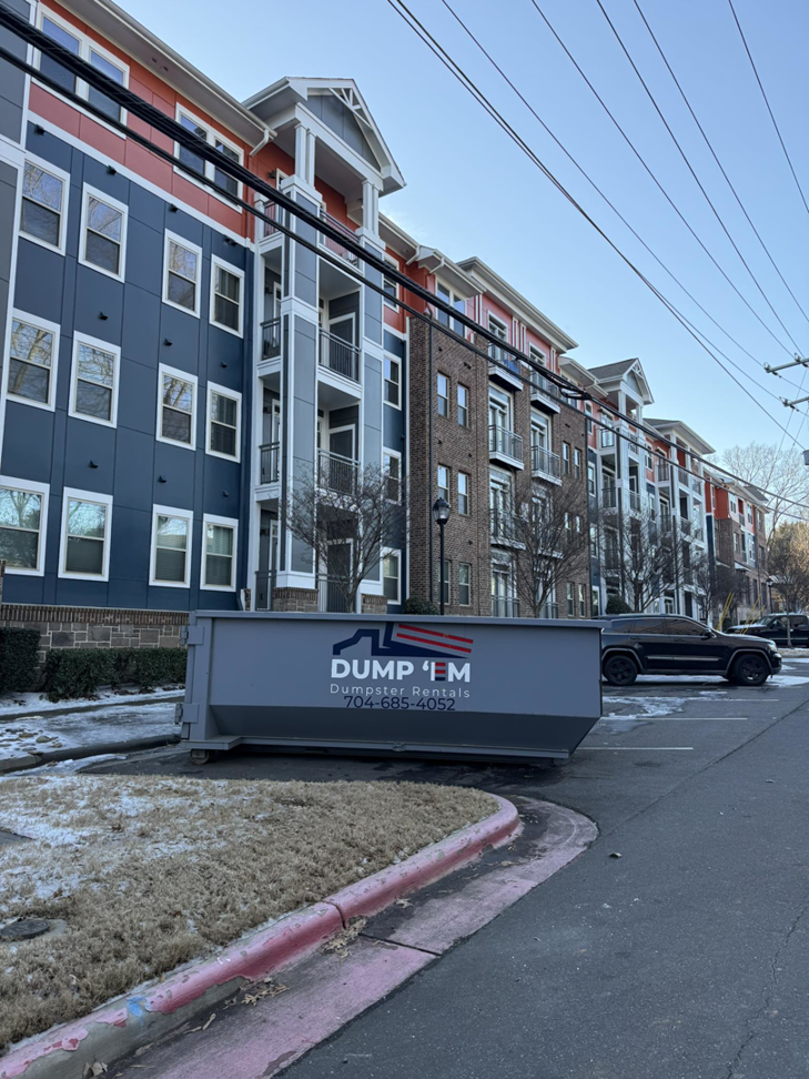 A Dump 'Em Dumpster Rentals dumpster placed in the parking lot of an apartment complex in Charlotte, NC.