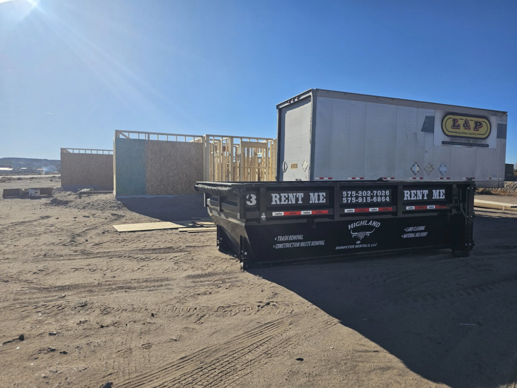 A black dumpster from Highland Dumpster Rentals LLC at a construction site in Las Cruces, NM, ready for waste removal.
