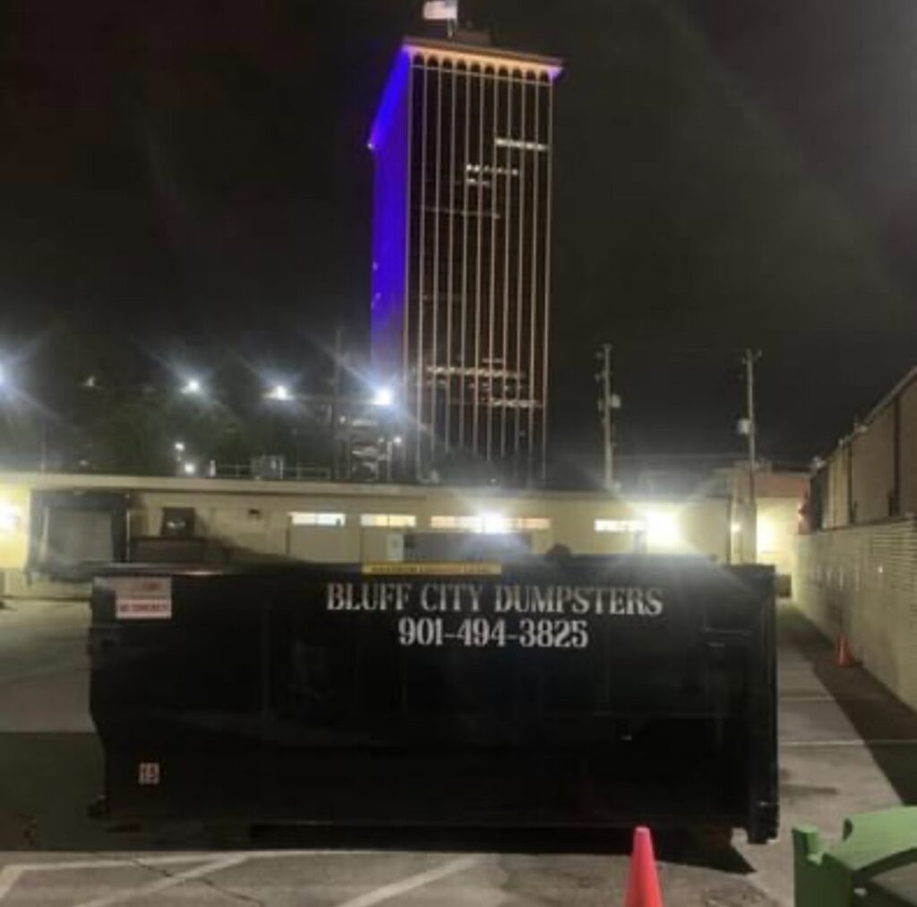 A Bluff City Dumpsters roll-off dumpster placed at night in a city parking lot in Memphis, TN.