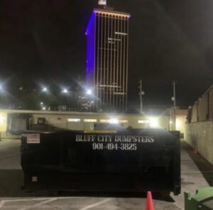 A Bluff City Dumpsters roll-off dumpster placed at night in a city parking lot in Memphis, TN.