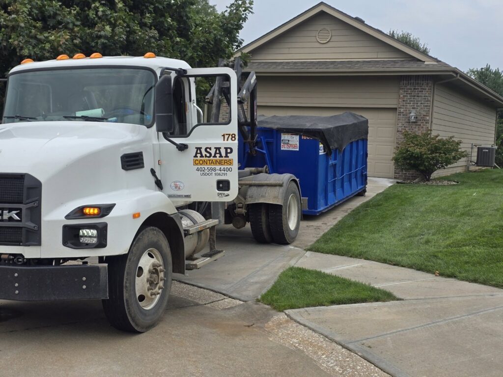 An ASAP Containers inc. blue dumpster placed at a residential property for junk removal services in Omaha, NE.