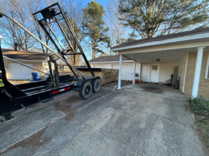 A dumpster from Curry Dumpster Rentals LLC being deployed in a residential driveway for junk removal in Southaven, MS.