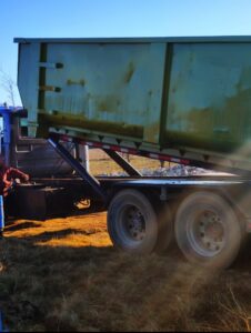 A FJD Waste Disposal and Recycling LLC truck tilting a green dumpster to empty its contents during a junk removal service in Dallas, TX.