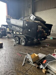 A dumpster being loaded with various household and construction junk for removal by NTX Haul Away Junk Removal in Fort Worth, TX.