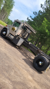 A Dumpster Co roll-off truck parked on a dirt road, ready for junk removal services in Duluth, MN.