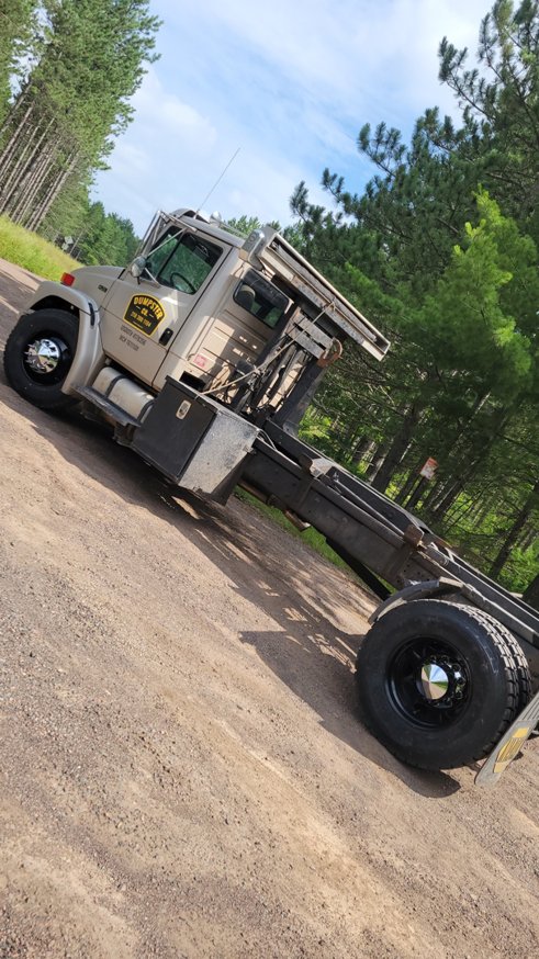 A Dumpster Co roll-off truck parked on a dirt road, ready for junk removal services in Duluth, MN.
