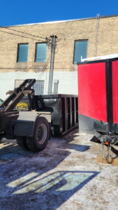 A Dumpster Co truck unloading a black dumpster in an urban area, providing junk removal services in Duluth, MN.