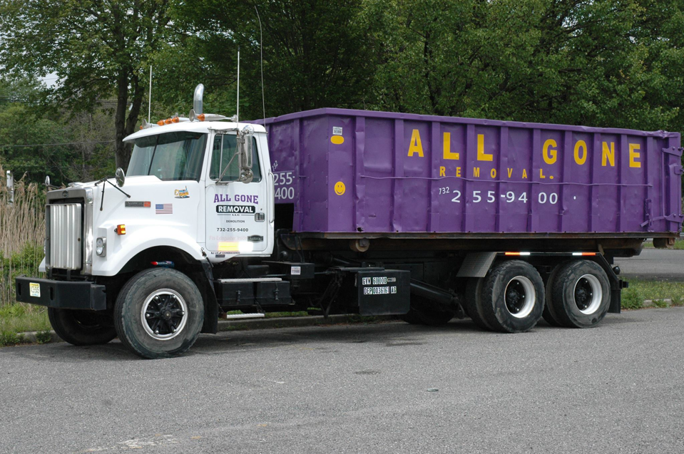 A large purple dumpster container on a truck from All Gone Removal Demolition & Junk Dumpster Containers in Toms River, NJ.