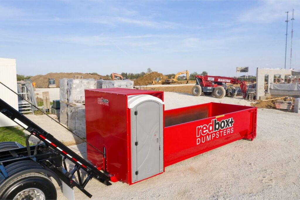 Redbox+ truck delivering dumpster with portable toilet to construction site for redbox+ Dumpsters of Greater Austin, Austin, TX