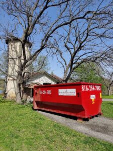 A red dumpster delivered to a home's driveway by Trinity Dumpster Rental LLC in Kansas City, MO.
