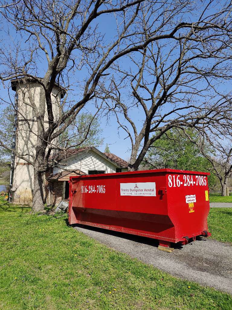 A red dumpster delivered to a home's driveway by Trinity Dumpster Rental LLC in Kansas City, MO.