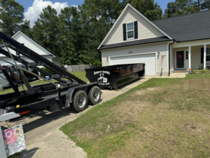 A black dumpster being delivered for junk removal by Dumpster Busters in Salemburg, NC.