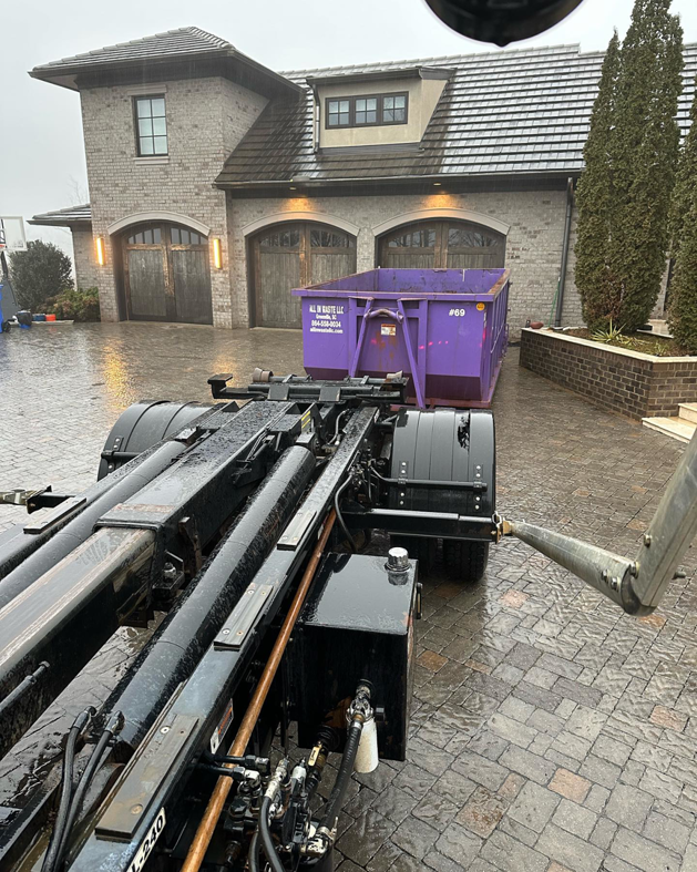 An All In Waste dumpster being delivered to a large residential property in Greenville, SC.