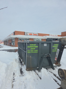A dumpster being moved by heavy machinery for commercial junk removal by Cheap Dumpsters ASAP in Columbus, OH.