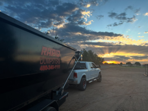 A Rapid Dumpsters container being transported by a pickup truck at sunset in Chandler, AZ.