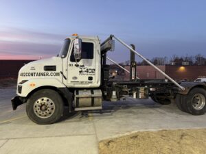 A 402 Container truck delivering a dumpster to a residential property for junk removal in Omaha, NE.