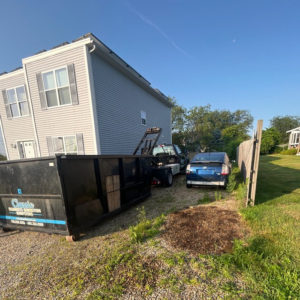 A Classic Disposal truck delivering a dumpster to a residential property for junk removal in Malden, MA.