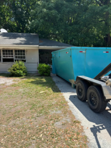 A blue dumpster being delivered to a residential driveway by Site Boss Dumpster Rentals in Raeford, NC.