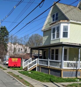 A red dumpster from Affordable Dumpsters delivered to a residential street for junk removal in Watervliet, NY.