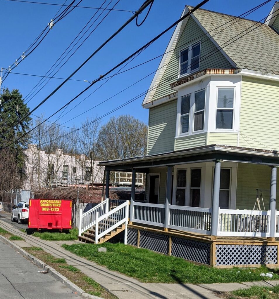 A red dumpster from Affordable Dumpsters delivered to a residential street for junk removal in Watervliet, NY.