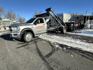 A Denver Dumpsters truck delivering or picking up a roll-off dumpster at a residential property in Denver, CO.