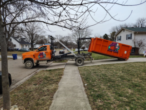 A Crazy Larry's Dumpster Rental truck deploying an orange dumpster onto a residential street in Columbus, OH.