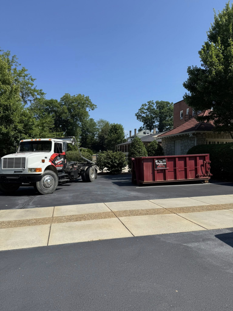 A Wallburg Disposal Worx LLC truck and a red dumpster ready for delivery or pickup in High Point, NC.