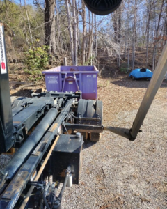 An All In Waste dumpster being delivered to a wooded residential area in Greenville, SC.
