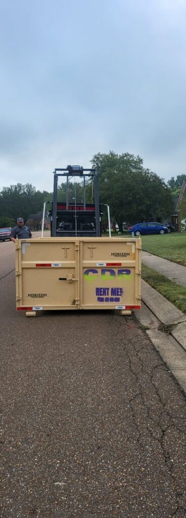 A dumpster from Curry Dumpster Rentals LLC being deployed on a residential street for junk removal in Southaven, MS.