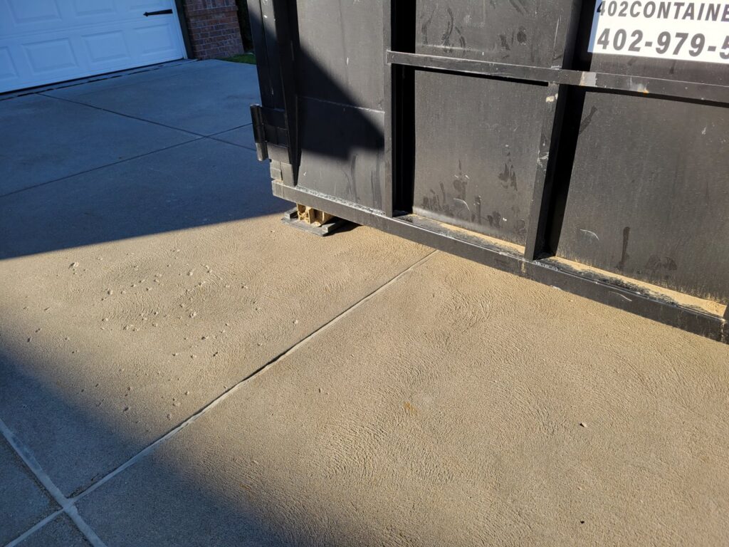 Close-up of a 402 Container dumpster with driveway protection in place for junk removal in Omaha, NE.