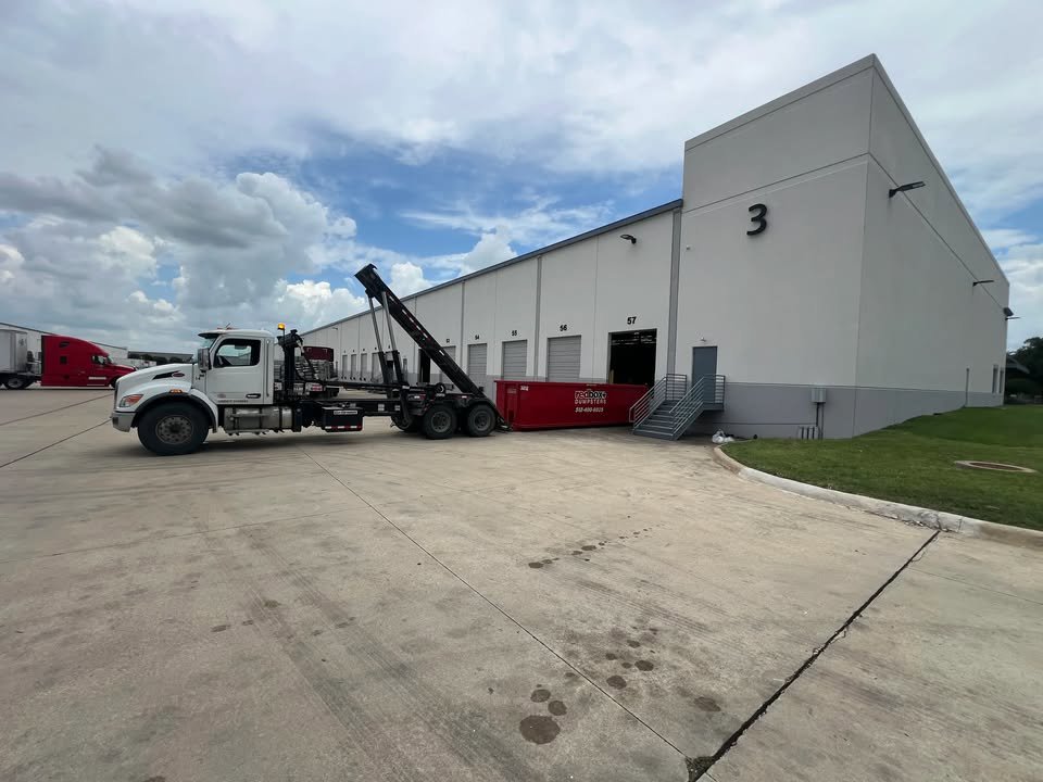 A redbox+ truck dropping off a dumpster at a commercial building for redbox+ Dumpsters of Greater Austin in Austin, TX