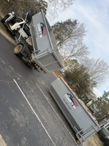 A Dump 'Em Dumpster Rentals truck dropping off or picking up a dumpster in Charlotte, NC.