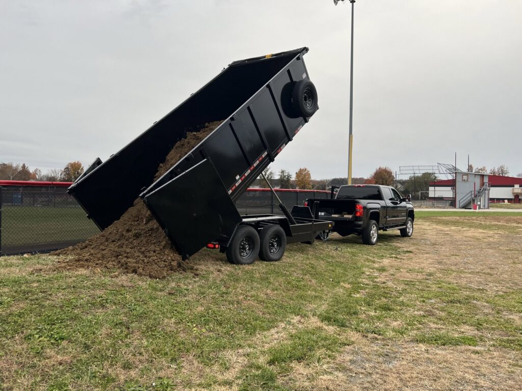 A Trademark Dumpsters trailer dumping soil, demonstrating landscaping waste removal services in Wilmington, DE.