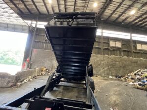 A Trademark Dumpsters trailer emptying construction debris at a disposal site, showcasing junk removal in Wilmington, DE.