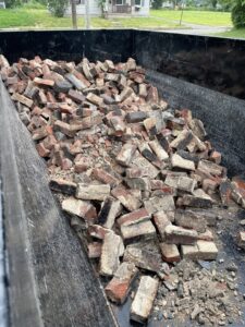 A dumpster from TRS Roll-Offs LLC filled with broken bricks, showcasing construction debris removal in Canton, OH.
