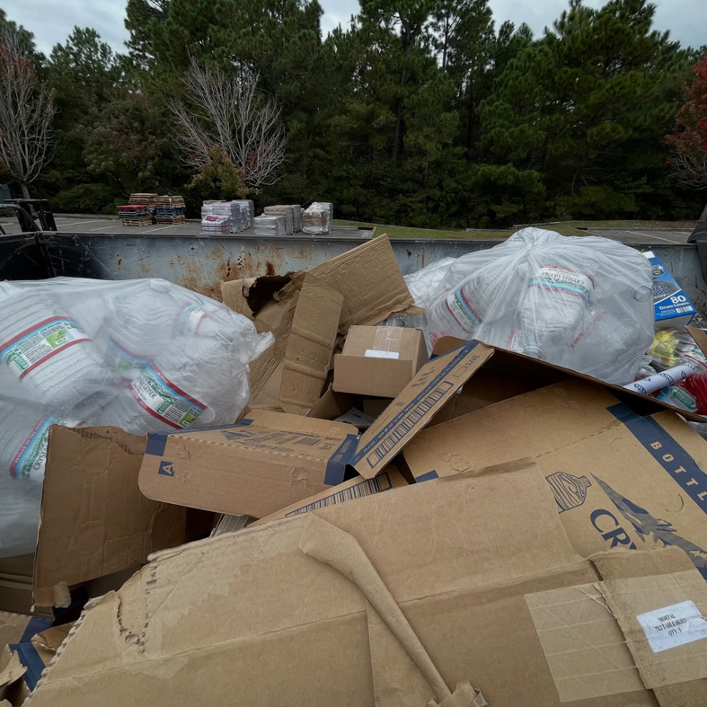 A large dumpster filled with cardboard boxes and plastic bags of recyclables collected by Turtletrash in Wilmington, NC.