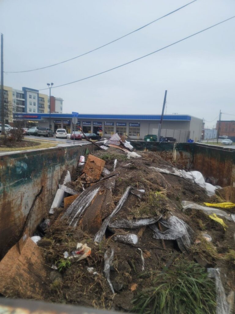 A large roll-off dumpster filled with construction debris and soil, handled by P and P Junk Removal and Demolition in Norfolk, VA.