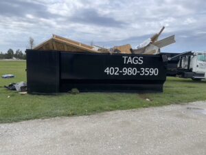A Tags Dumpsters roll-off dumpster filled with construction debris and wood, ready for removal in Omaha, NE.