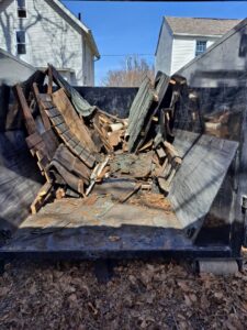 A dumpster from TRS Roll-Offs LLC filled with old roofing shingles and wood, showing demolition debris removal in Canton, OH.