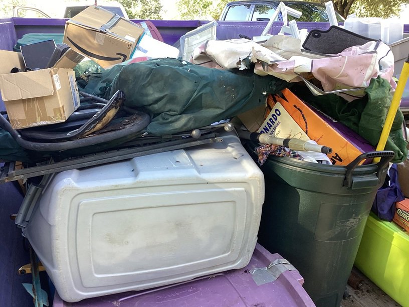A dumpster filled with various junk, boxes, and debris for removal by Liberty Hill Dumpster Rental in Austin, TX
