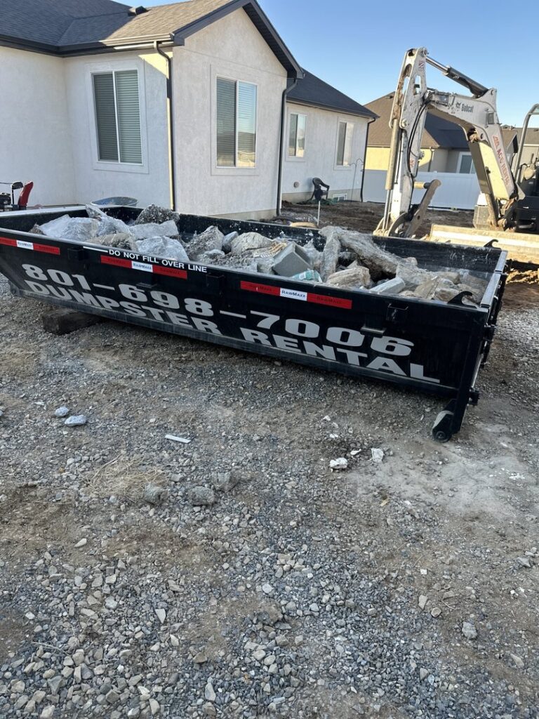 A dumpster filled with construction debris and rocks at a job site by Utah Valley Dumpsters in Provo, UT.