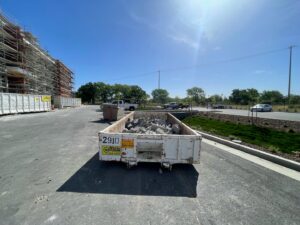 A roll-off dumpster filled with construction debris at a job site, provided by Waste Removal and Recycling in Sacramento, CA.