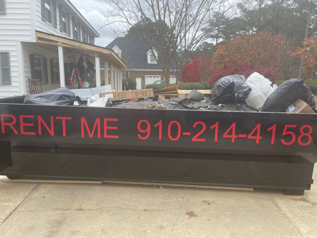 A black dumpster filled with various junk items for removal by Dumpster Busters in Salemburg, NC.