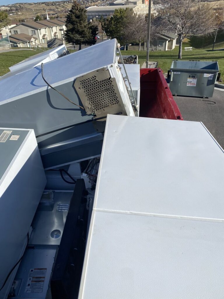 A roll-off dumpster filled with old appliances, including refrigerators, for removal by Jedi Junk Removal Garbage Services Pocatello, ID.