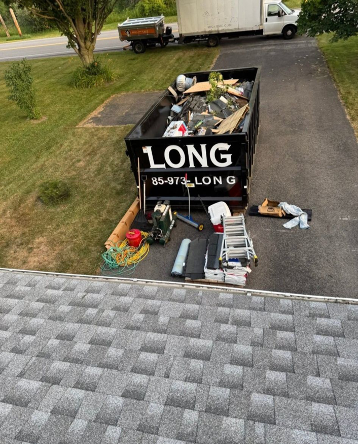 An overhead view of a Long Dumpster Rentals dumpster filled with roofing debris and junk on a driveway in Rochester, NY.